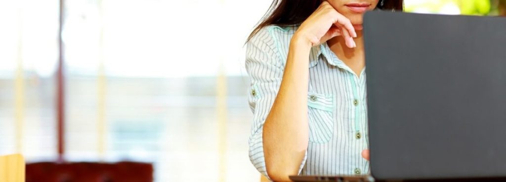 A woman is sitting in front of a laptop