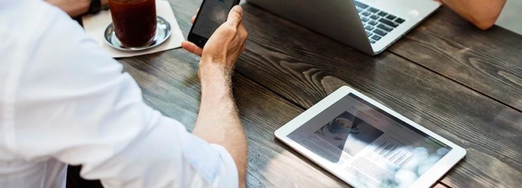 Two people sitting at a table with a laptop and tablet